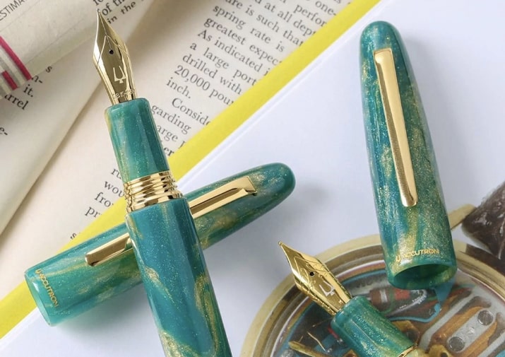 Accutron Pens by Esterbrook Collection Turquoise and gold Esterbrook fountain pens displayed on an open book