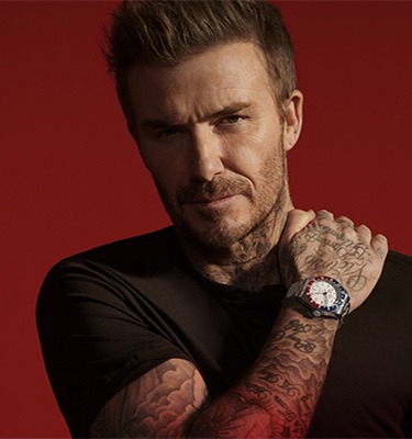 TUDOR Ambassador David Beckham David Beckham wearing a Tudor watch against a red background
